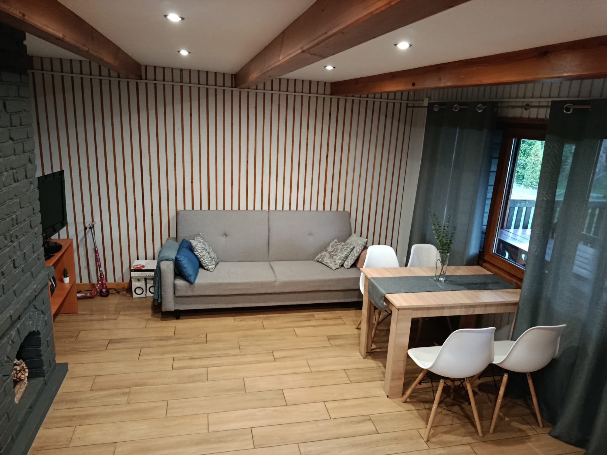 Salon z kominkiem, stołem i sofą w domku letniskowym nad Zalewem w Ożannie.